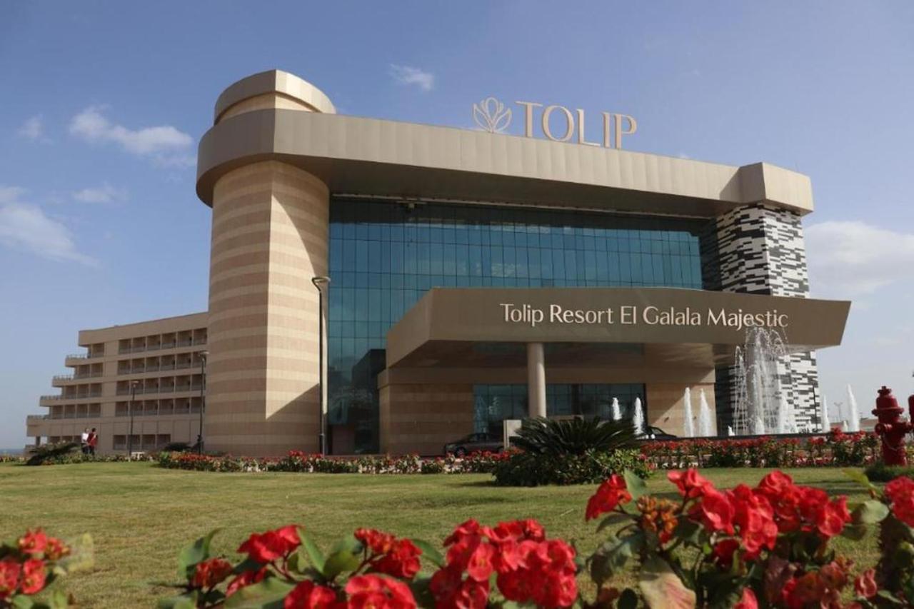 Tolip Resort El Galala Majestic Ain Sukhna Eksteriør bilde The photo shows a modern hotel building named "Tolip Resort El Galala Majestic." The structure features a distinctive architectural design with large glass windows and a prominent entrance. Surrounding the building are well-maintained lawns and vibra