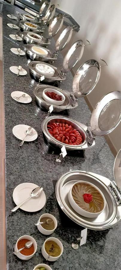 Tolip Resort El Galala Majestic Ain Sukhna Eksteriør bilde The photo shows a buffet setup featuring multiple metal serving trays on a dark granite countertop. One tray contains circular slices of food, possibly sausages or a similar dish, while another bowl holds what appears to be red food items, though it'