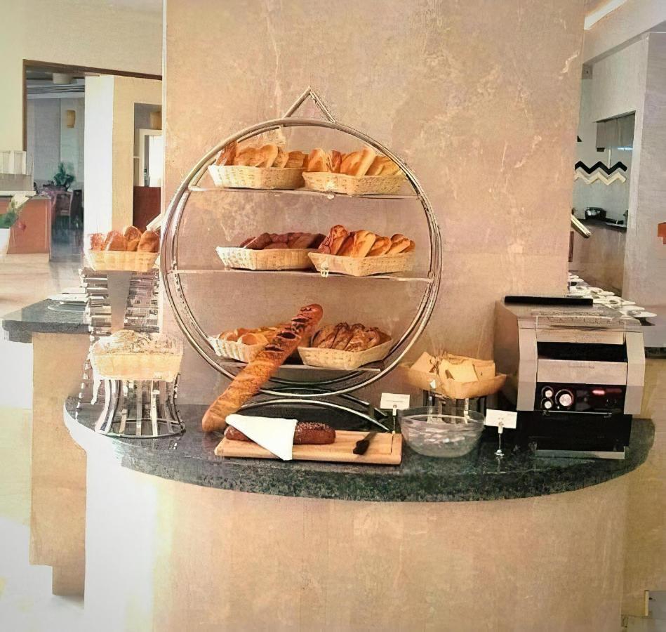 Tolip Resort El Galala Majestic Ain Sukhna Eksteriør bilde The photo shows a display of various types of bread and pastries arranged on a countertop. There are several baskets stacked on a circular stand, filled with different baked goods like croissants and rolls. A long baguette is placed horizontally on a