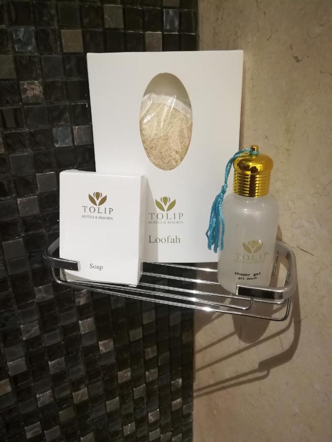 Tolip Resort El Galala Majestic Ain Sukhna Eksteriør bilde The photo shows a small metal shelf containing three items related to personal care. 

1. **Soap**: A white box labeled "TOLIP" with the word "Soap" visible on the front.
2. **Loofah**: A package with the same "TOLIP" branding, containing loofah.
3. 